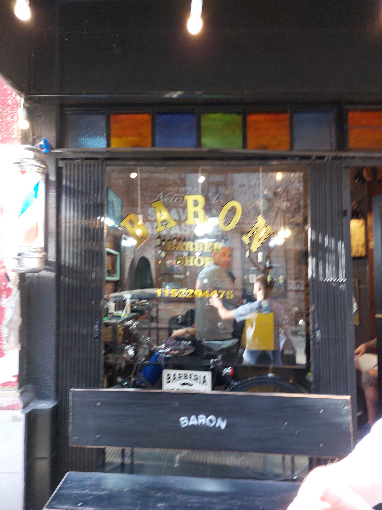 Interior de Baron Peluquería y Barbería con sillones y decoración de ladrillo a la vista
