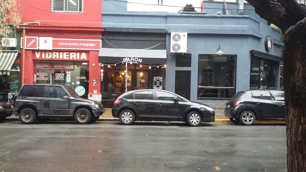 Vidriera de Baron Peluquería y Barbería con el cartel y el teléfono